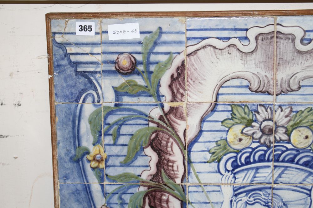 A Continental maiolica tile panel, depicting a putto holding aloft a basket of fruit, overall 90 x 72cm